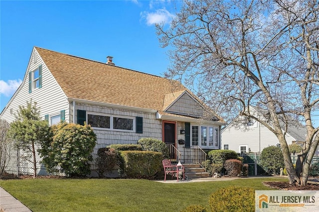 view of front of home with roof with shingles and a front yard