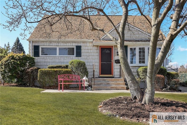 view of front of home featuring entry steps, a shingled roof, and a front lawn