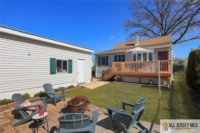 rear view of house with a deck, a yard, a fire pit, and a patio