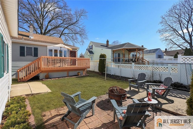 view of yard featuring a fenced backyard, a fire pit, a wooden deck, a residential view, and a patio area