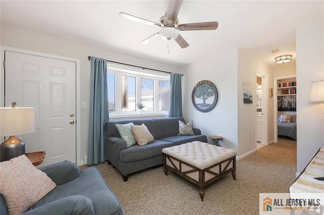 living room with ceiling fan, built in features, baseboards, and light colored carpet