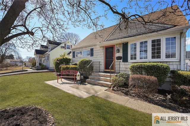 view of front of house with roof with shingles and a front yard