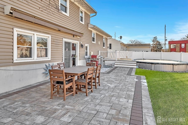 view of patio featuring outdoor dining area, area for grilling, fence, a deck, and a covered pool