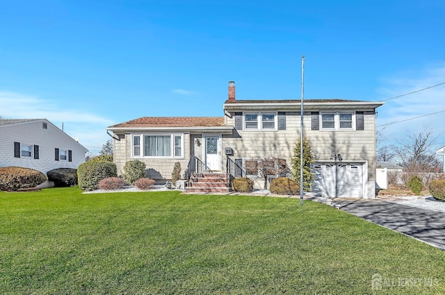 tri-level home with aphalt driveway, a chimney, an attached garage, and a front lawn