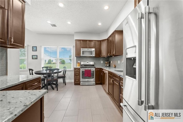 24 Birmingham Ln, Monroe, NJ 08831 - kitchen featuring stainless steel appliances, recessed lighting, backsplash, light stone countertops, and a textured ceiling