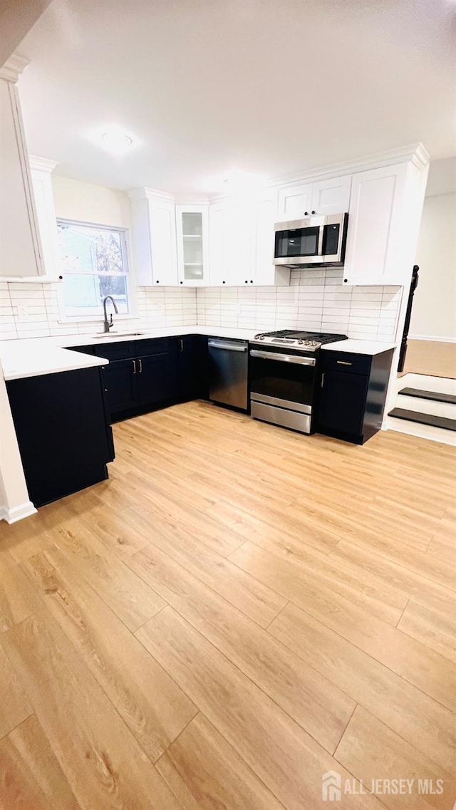 7 Harper Rd, South Brunswick, NJ 08852 - kitchen with appliances with stainless steel finishes, dark cabinets, white cabinetry, and light wood finished floors