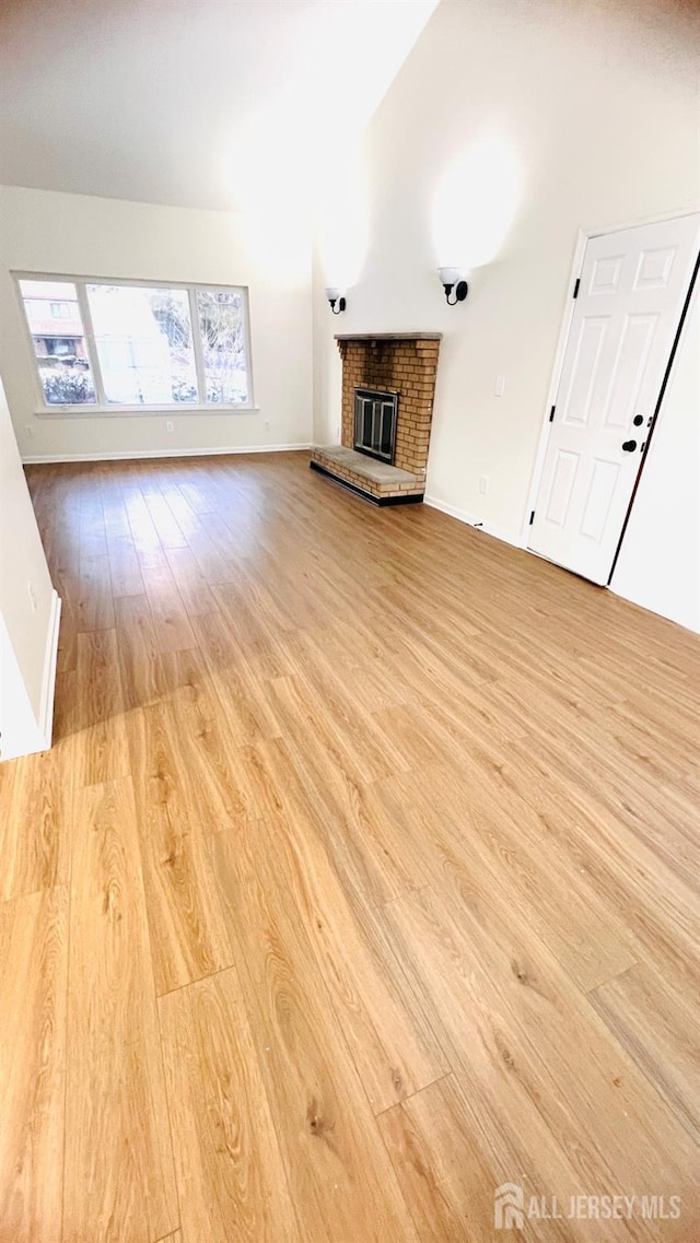 unfurnished living room featuring a brick fireplace and light hardwood / wood-style flooring