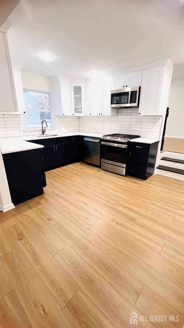 kitchen with white cabinetry, sink, decorative backsplash, and stainless steel appliances