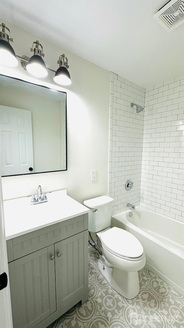 full bathroom with tiled shower / bath, vanity, and toilet