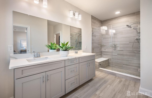 ensuite bathroom featuring double vanity, a shower stall, a sink, and ensuite bath
