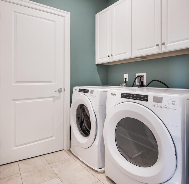washroom with cabinet space, light tile patterned floors, and washing machine and clothes dryer