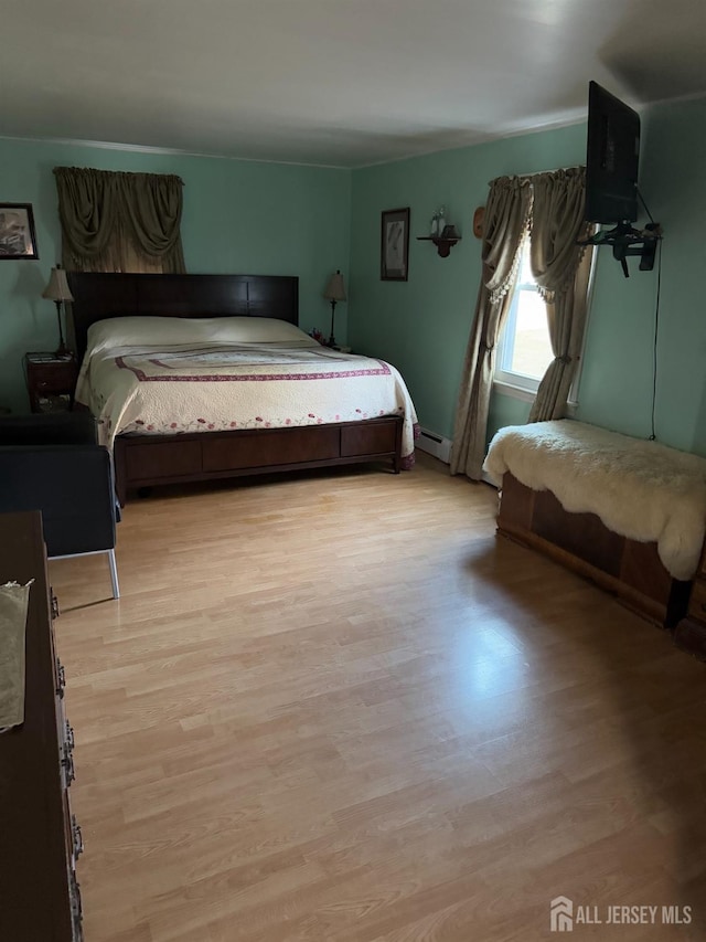 bedroom with baseboard heating and light wood finished floors