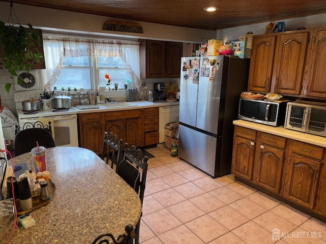 kitchen featuring light tile patterned floors, a sink, wood ceiling, light countertops, and appliances with stainless steel finishes