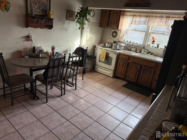 kitchen featuring light tile patterned floors, white electric range oven, light countertops, a sink, and dark brown cabinetry