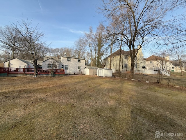 view of yard featuring a storage shed, a residential view, an outbuilding, fence, and a wooden deck