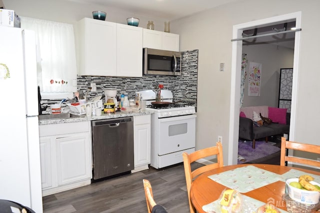 kitchen with light stone counters, dark wood finished floors, decorative backsplash, appliances with stainless steel finishes, and white cabinetry