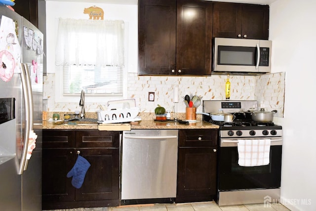 kitchen featuring appliances with stainless steel finishes, decorative backsplash, light stone counters, and dark brown cabinets