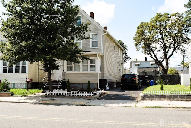 obstructed view of property with aphalt driveway and fence