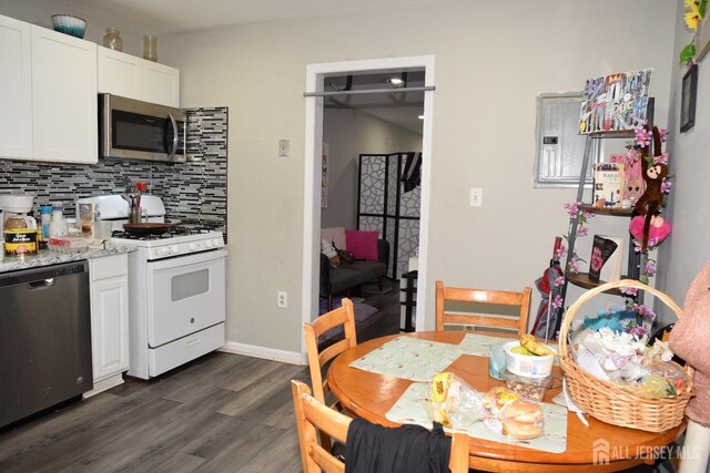 kitchen featuring light stone counters, dark hardwood / wood-style flooring, white cabinets, stainless steel appliances, and backsplash