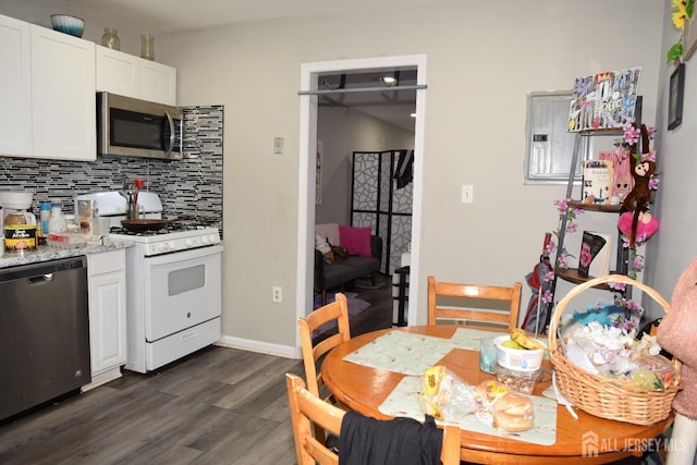 kitchen with light stone countertops, stainless steel appliances, white cabinets, decorative backsplash, and dark wood finished floors