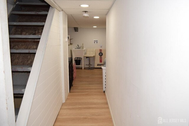 corridor with a paneled ceiling and light wood-type flooring