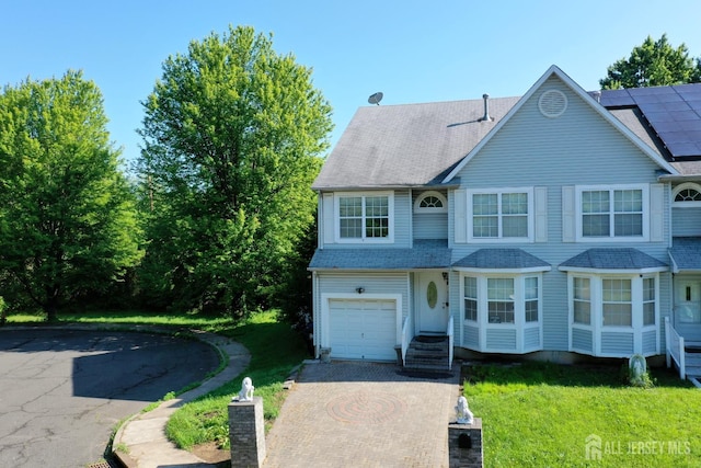 28 Elm St, East Brunswick, NJ 08816 - view of front of home featuring decorative driveway, a front lawn, a garage, and solar panels