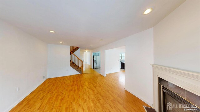 28 Elm St, East Brunswick, NJ 08816 - unfurnished living room with a fireplace with flush hearth, stairway, light wood finished floors, and recessed lighting