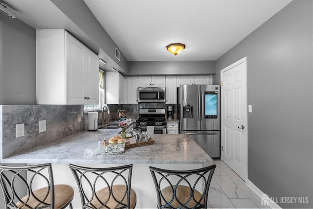 41 Haymarket Ct, East Windsor, NJ 08512 - kitchen with appliances with stainless steel finishes, light marble finish floors, a peninsula, white cabinetry, and light stone counters