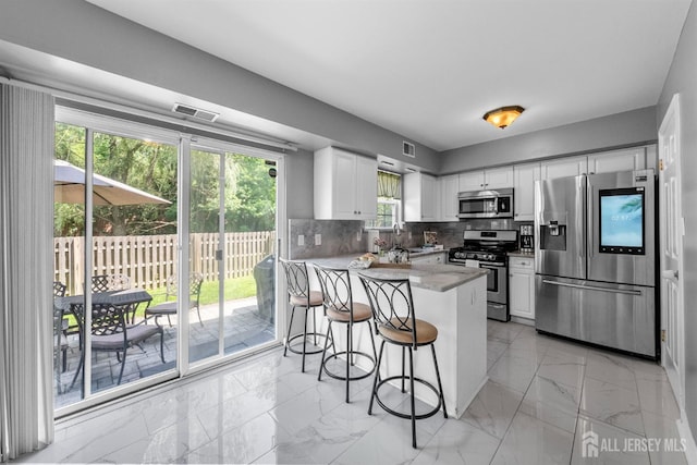 41 Haymarket Ct, East Windsor, NJ 08512 - kitchen featuring appliances with stainless steel finishes, a peninsula, white cabinets, and light marble finish floors