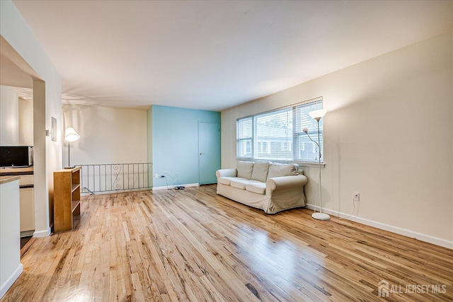 unfurnished living room with light wood-type flooring and baseboards