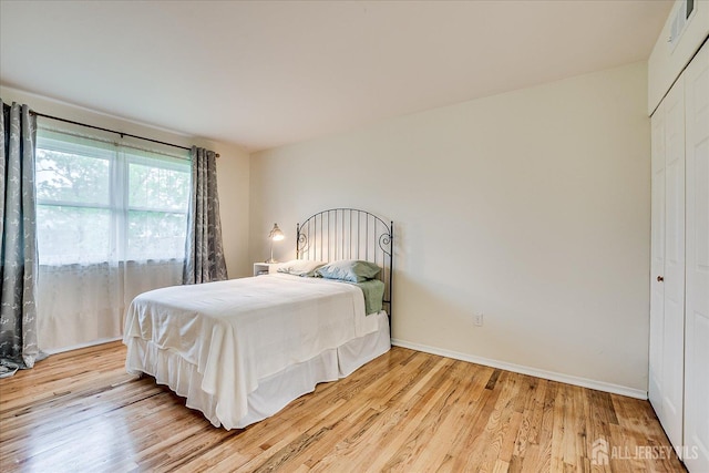 bedroom with light wood-style flooring, a closet, and baseboards