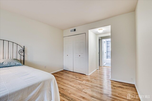 bedroom with light wood-type flooring, baseboards, and a closet