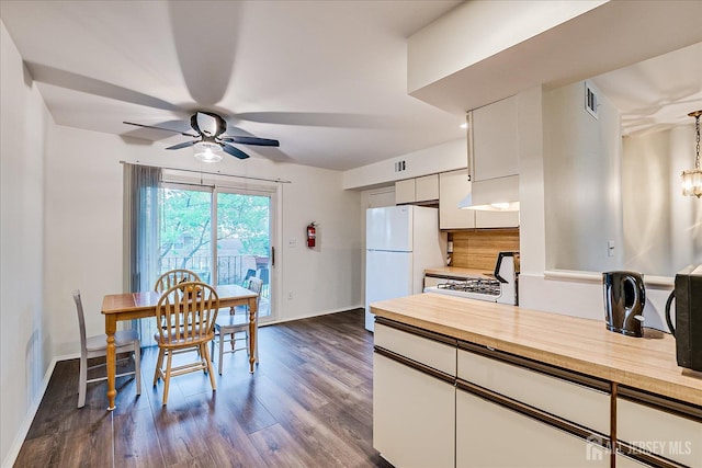 kitchen featuring white appliances, wood counters, ceiling fan, dark wood finished floors, and baseboards