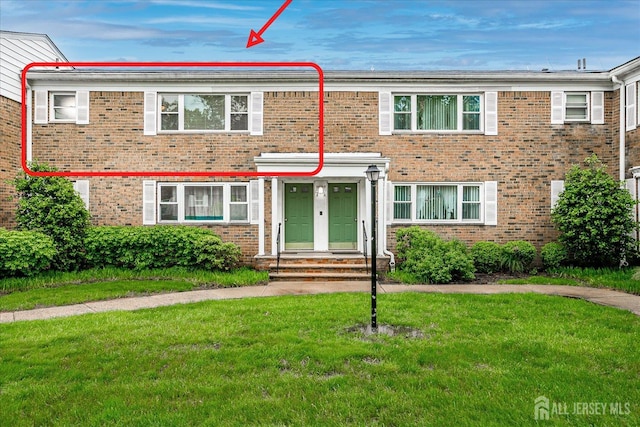 townhome / multi-family property featuring brick siding and a front lawn