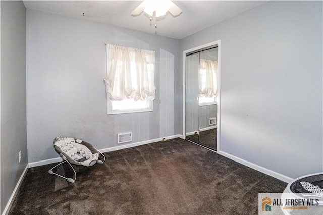 unfurnished bedroom featuring ceiling fan, a closet, and dark colored carpet