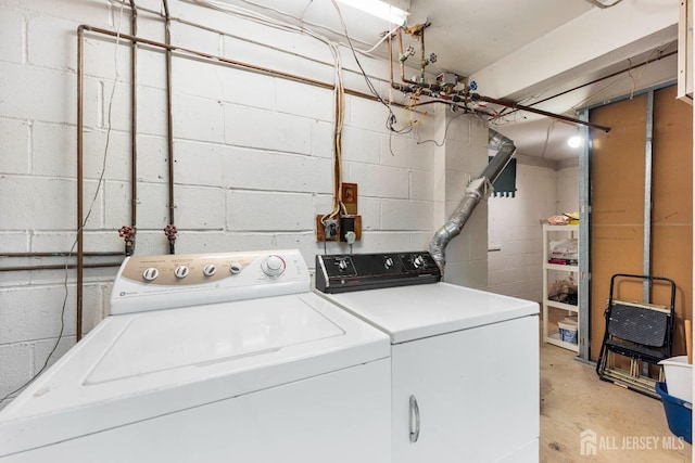 laundry room with separate washer and dryer, laundry area, and concrete block wall