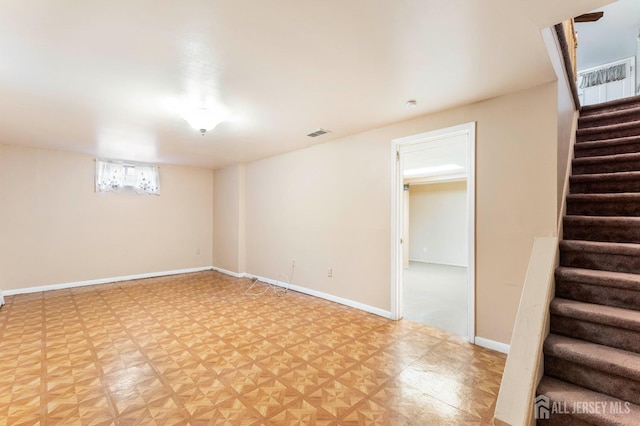 below grade area featuring stairway, baseboards, and visible vents
