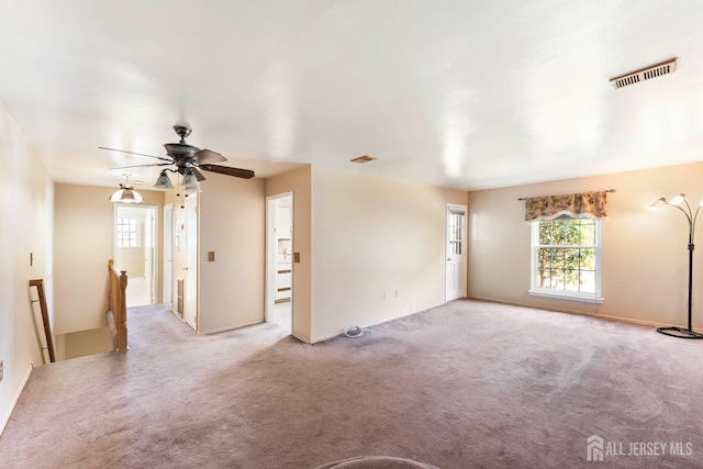 carpeted spare room with visible vents and ceiling fan