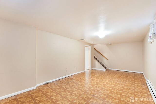 finished below grade area with stairs, baseboards, and a baseboard heating unit