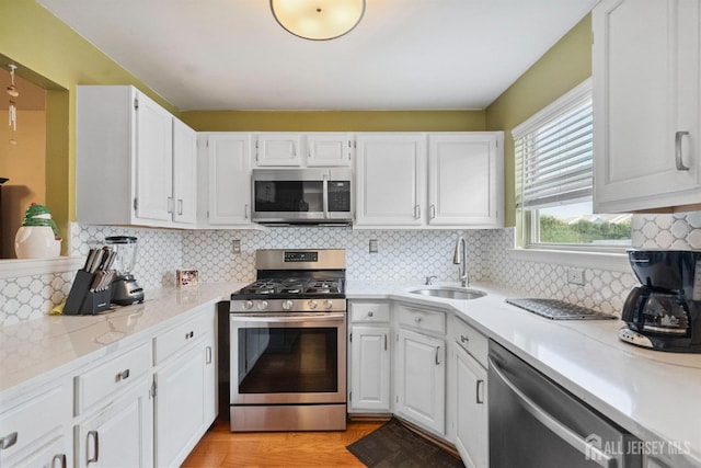 816 Harbortown Blvd Unit 816, Perth Amboy, NJ 08861 - kitchen featuring appliances with stainless steel finishes, light countertops, white cabinets, decorative backsplash, and light wood-style floors