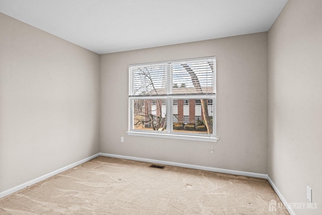 empty room with baseboards, visible vents, and carpet floors