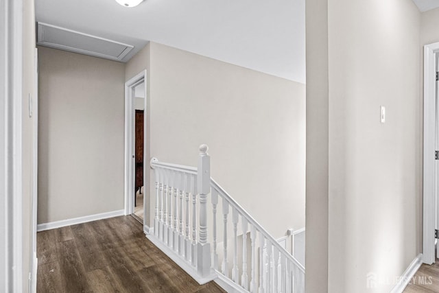 corridor featuring an upstairs landing, attic access, baseboards, and wood finished floors