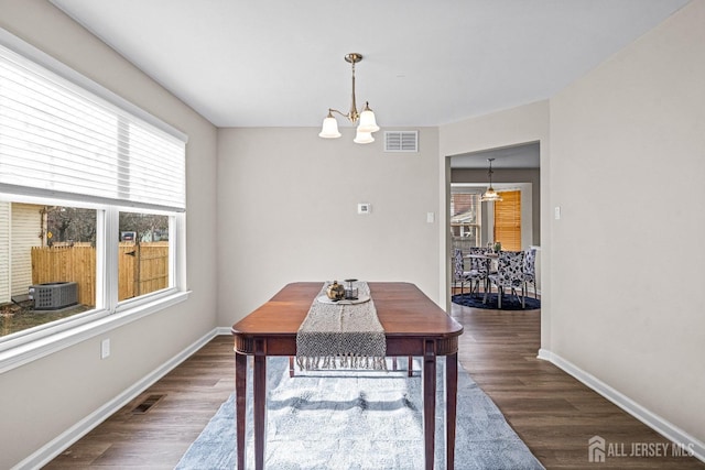 dining space featuring a notable chandelier, visible vents, baseboards, and wood finished floors