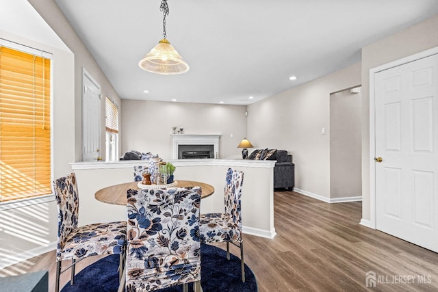 dining space featuring a fireplace, recessed lighting, wood finished floors, and baseboards