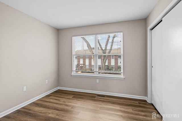 unfurnished bedroom featuring wood finished floors, a closet, and baseboards