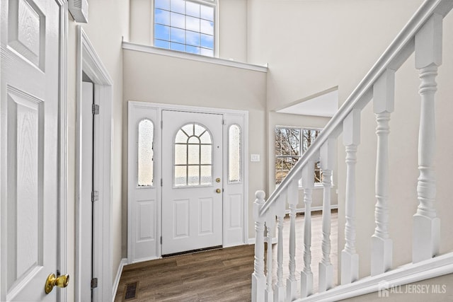 foyer featuring visible vents, stairs, a towering ceiling, and wood finished floors