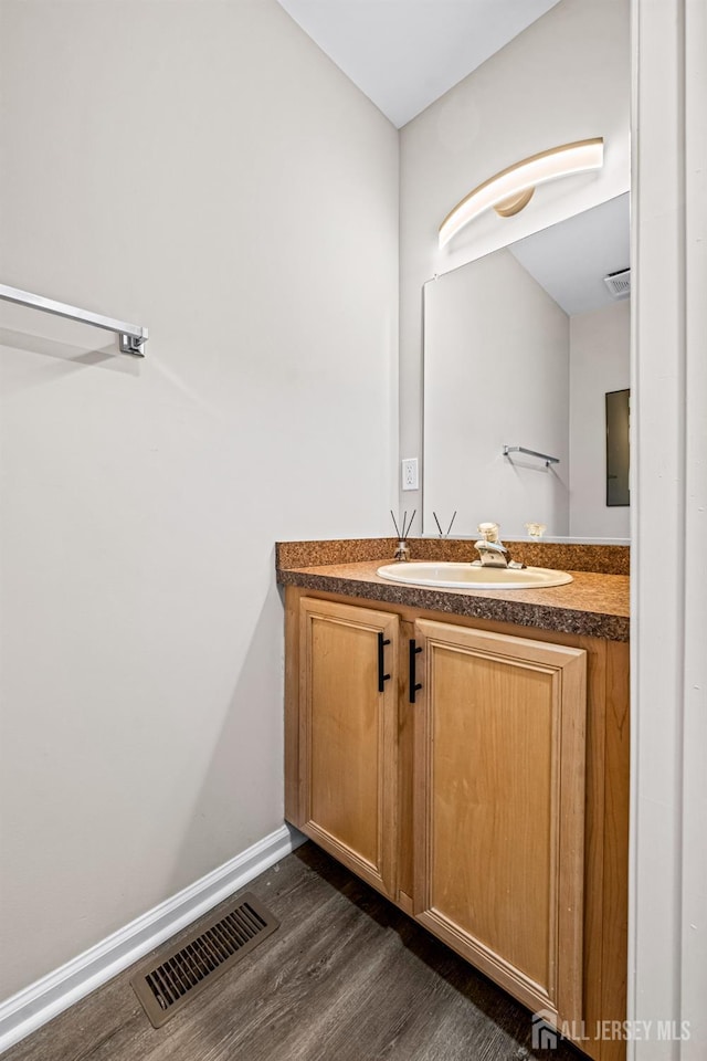 bathroom with vanity, wood finished floors, visible vents, and baseboards