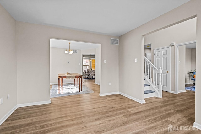 spare room with stairs, baseboards, visible vents, and light wood finished floors