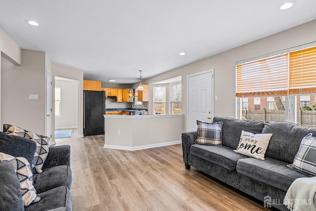 living area with plenty of natural light, recessed lighting, baseboards, and light wood-style floors