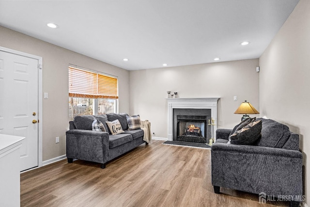 living area featuring light wood-style flooring, recessed lighting, and a lit fireplace